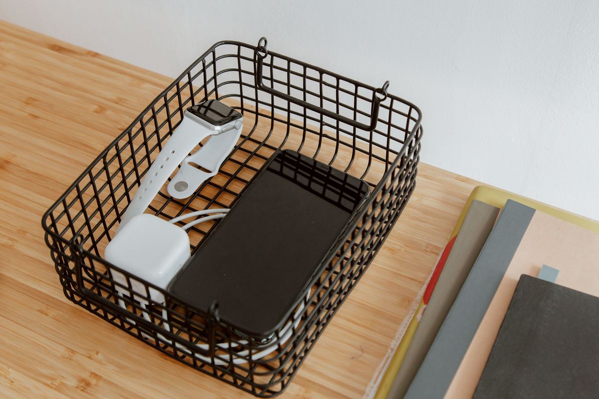 A wire basket holding devices on a desk