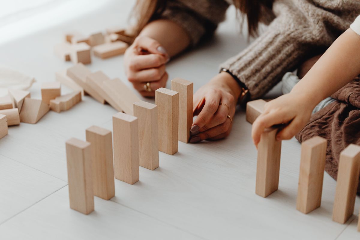 An adult and a child building with wooden blocks together