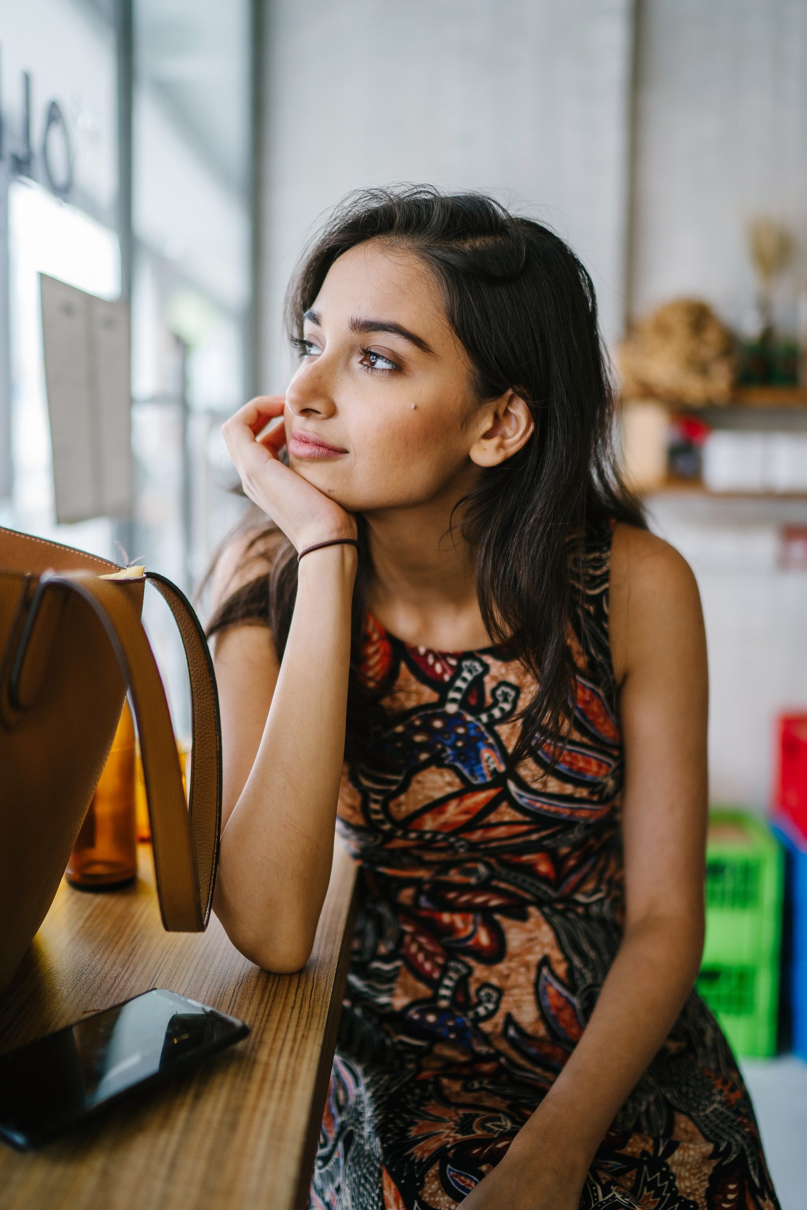 A young woman resting her chin on her hand, looking thoughtfully into the distance