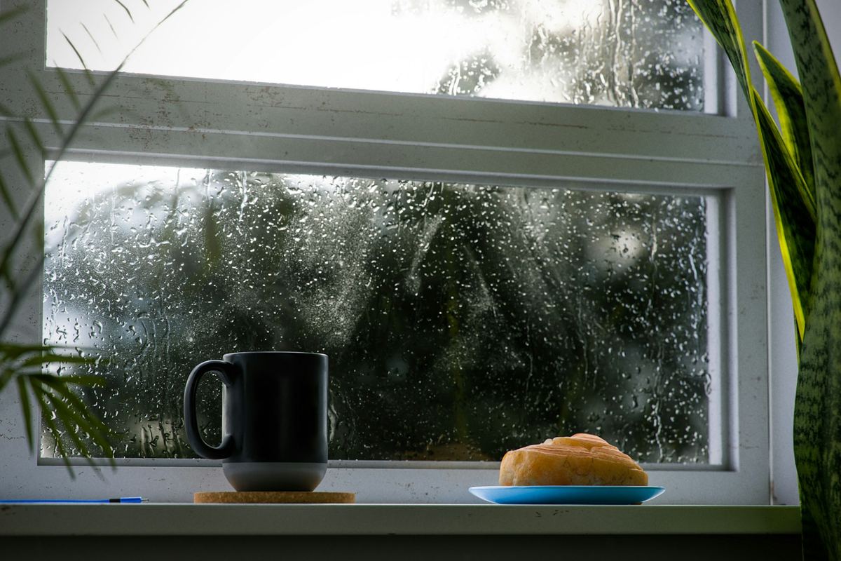 A cup of coffee and a piece of bread on a windowsill