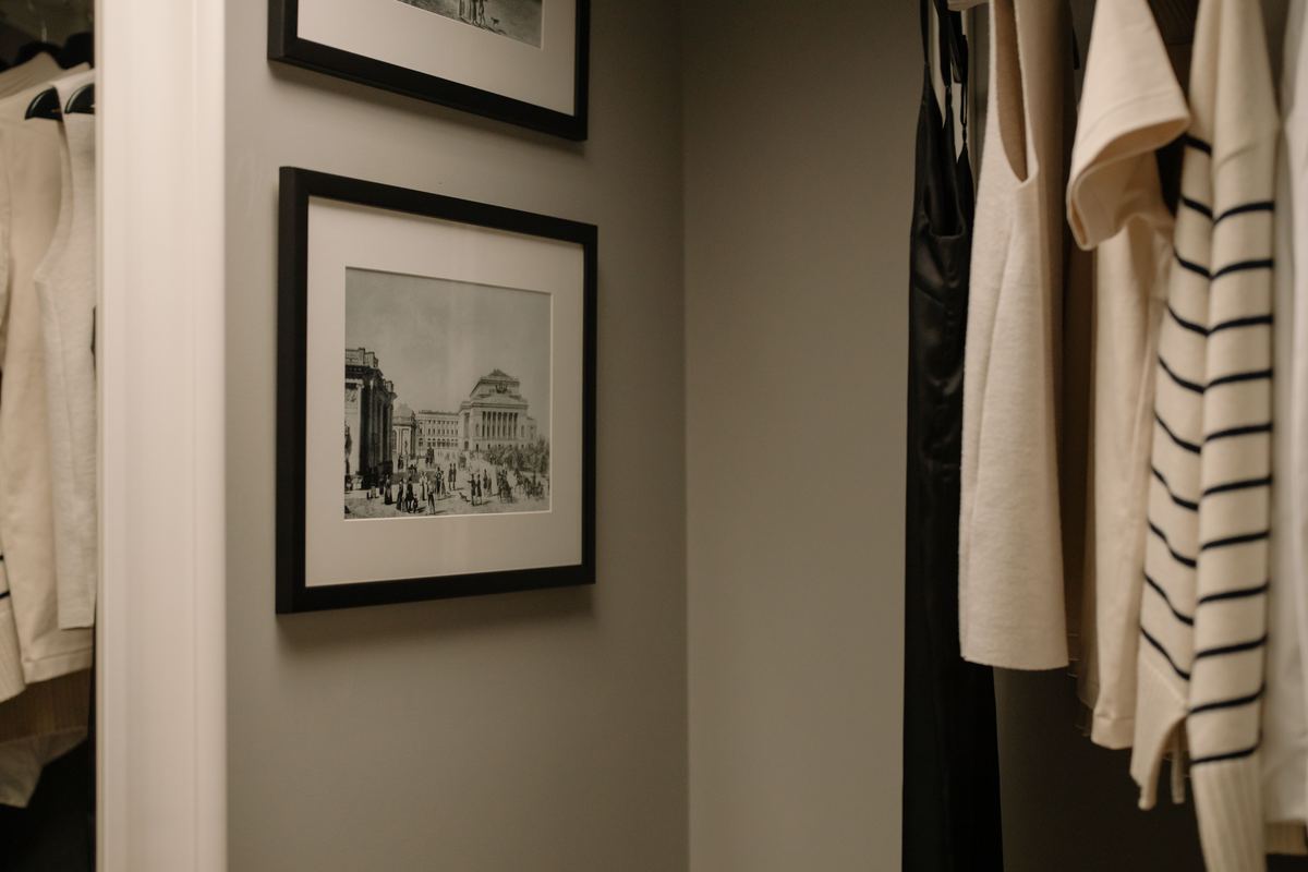 Clothes hanging in a wardrobe beside a framed picture