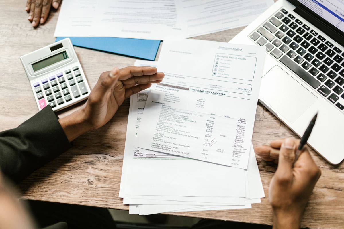 Hands holding financial documents beside a calculator