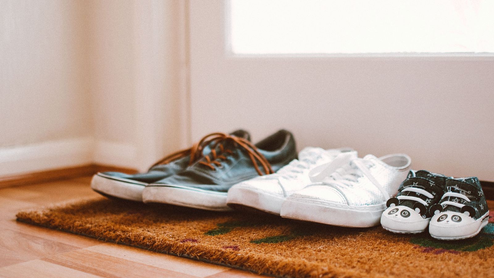 Adult and children's shoes together on a doormat at a front door