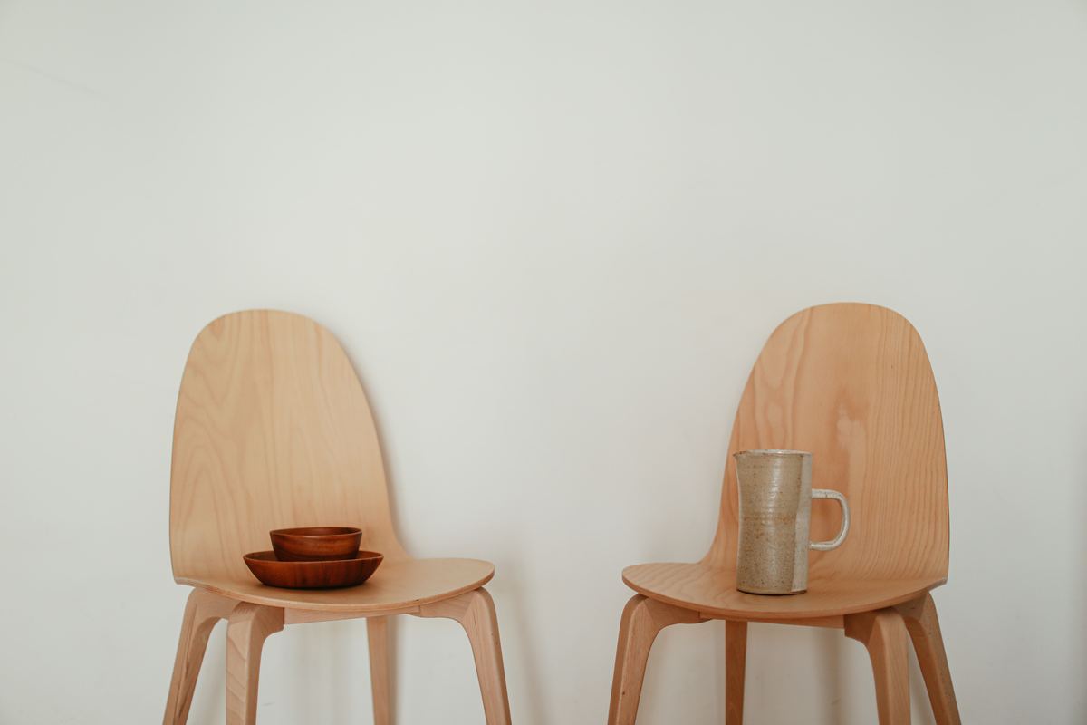 Two wooden chairs side by side with a mug and a bowl
