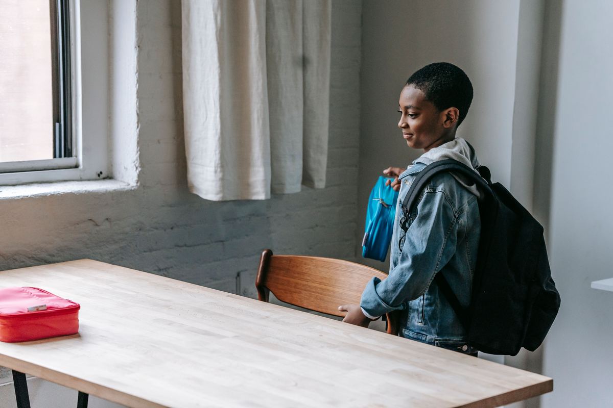 A child with a backpack sitting at a table