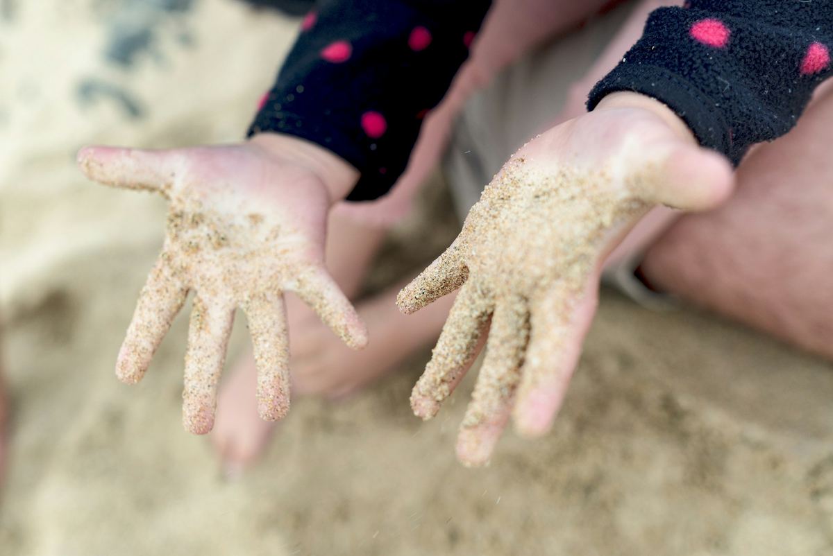 A child's hands covered in sand