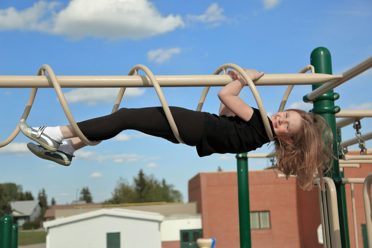 A child hanging upside down from playground bars