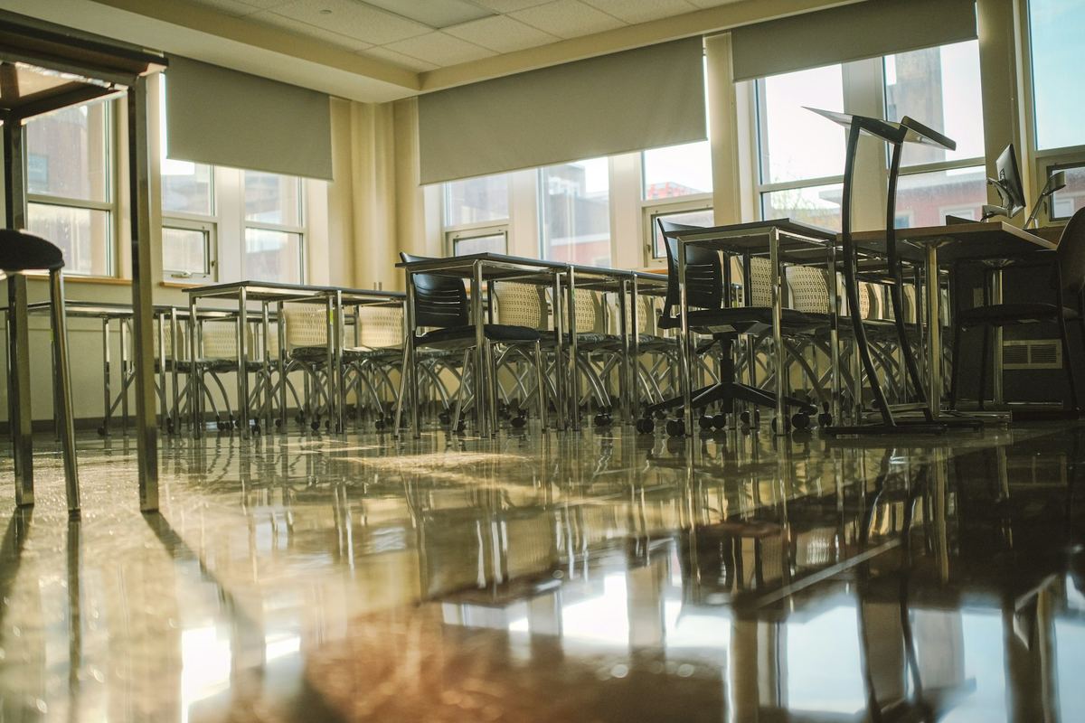 An empty classroom with tables and chairs in daylight