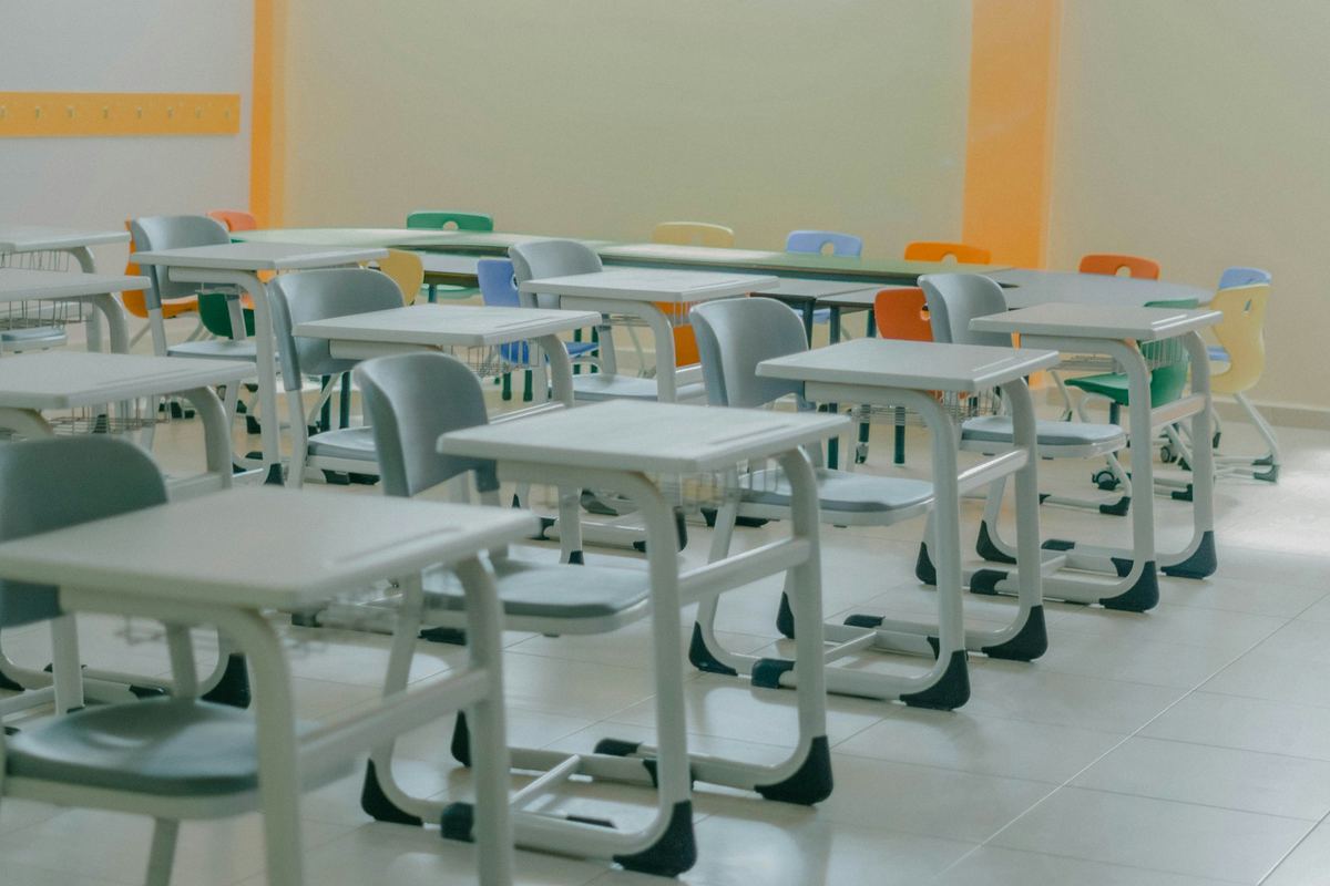 Rows of empty desks and chairs in a bright classroom