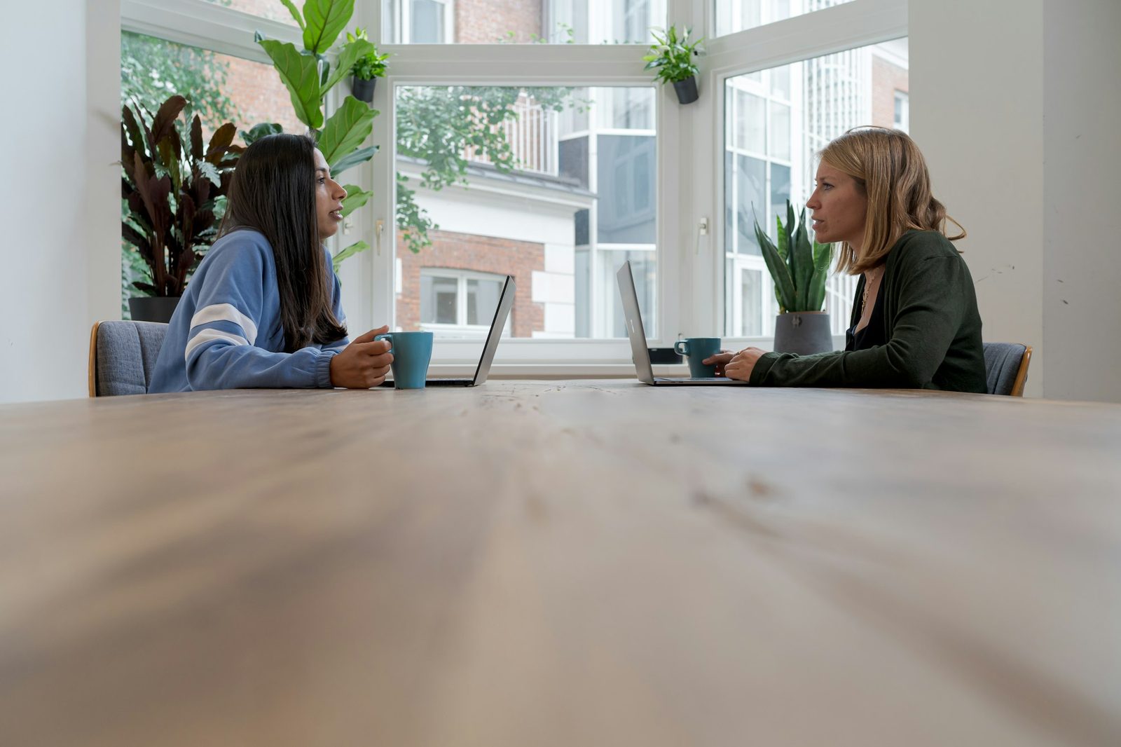 Two people talking across a table in a calm, bright room