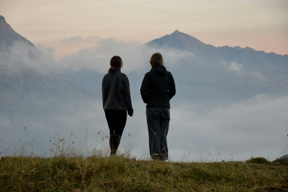 Two people standing on a hillside looking out over mist