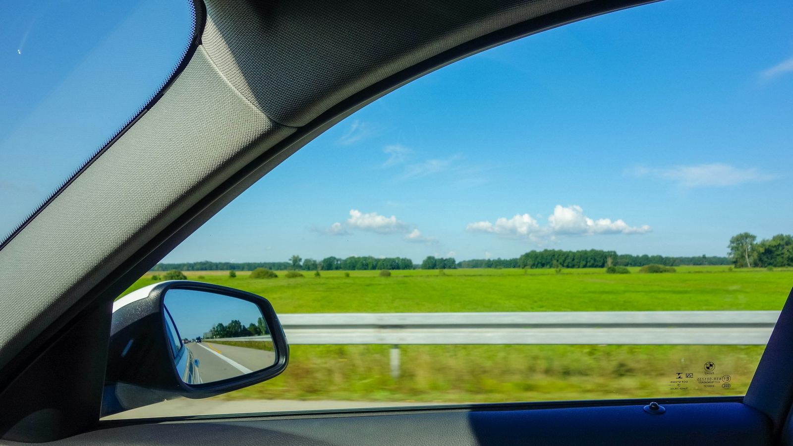The view through a car windscreen onto open fields