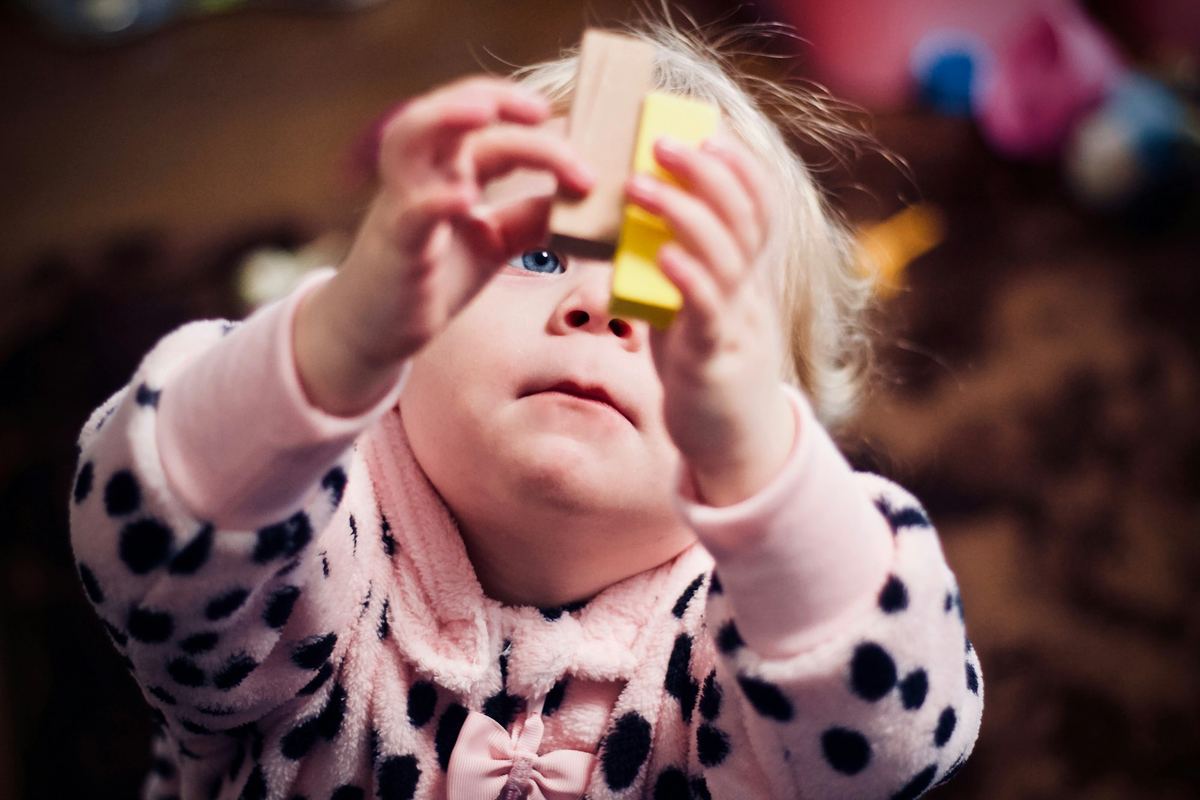 A toddler holding two wooden blocks up to the light
