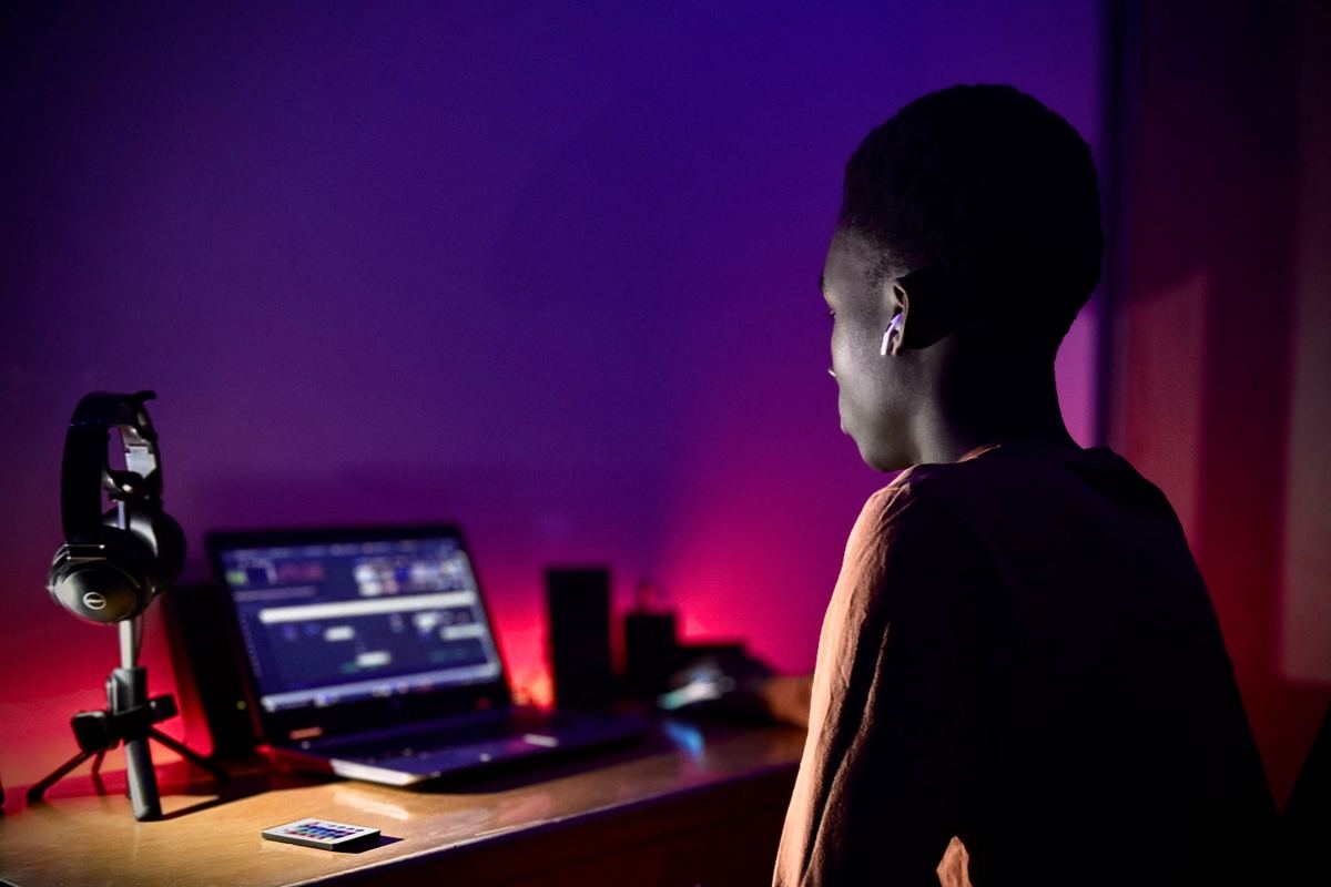 A young person at a desk lit by a screen in the evening