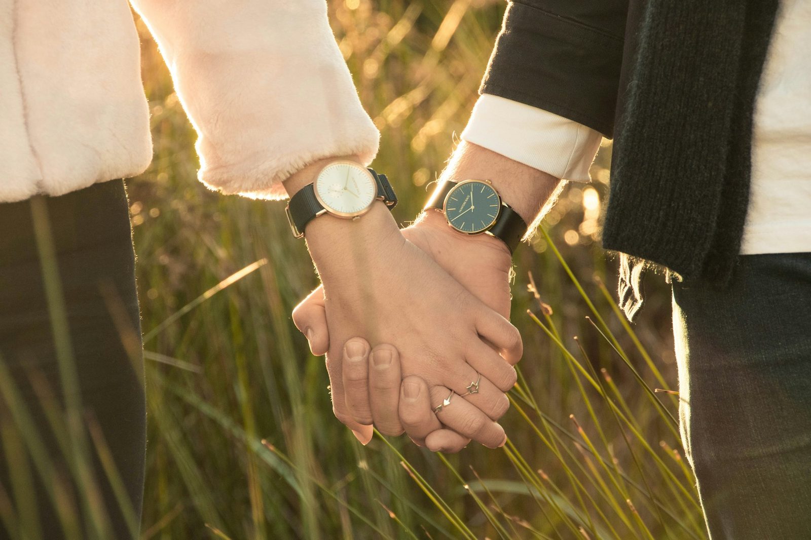 Two people holding hands while standing together outdoors