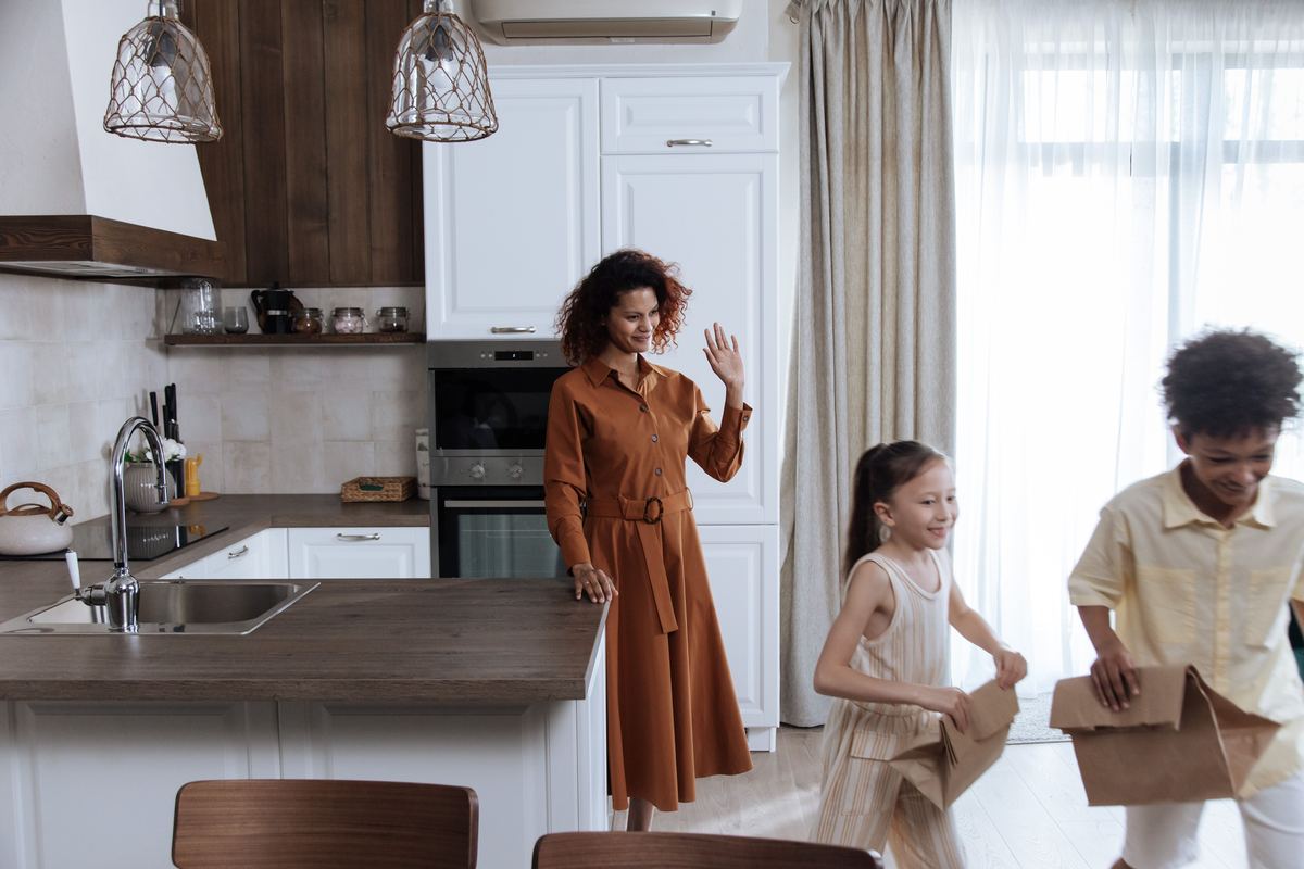 A parent and children in a kitchen as the children leave with lunch bags