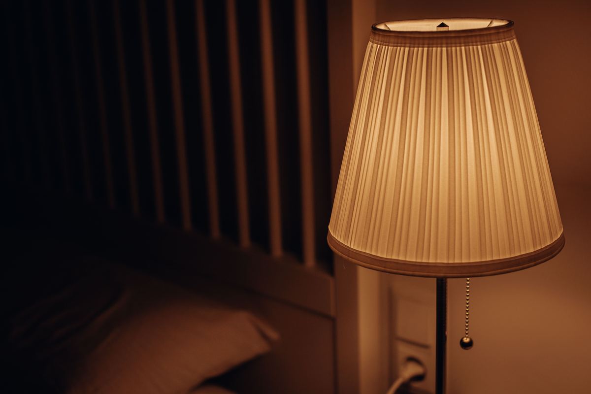 A bedside lamp glowing in a dim bedroom