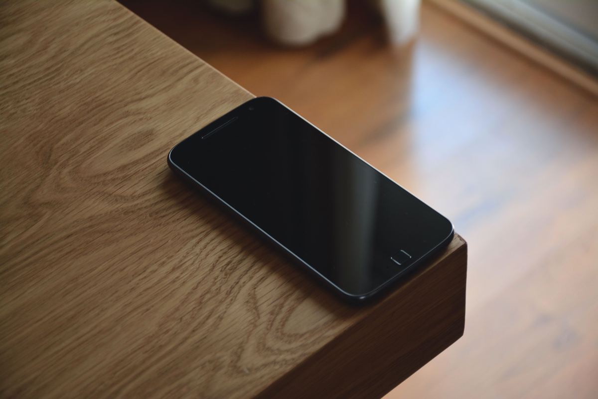 A smartphone resting on the edge of a wooden table