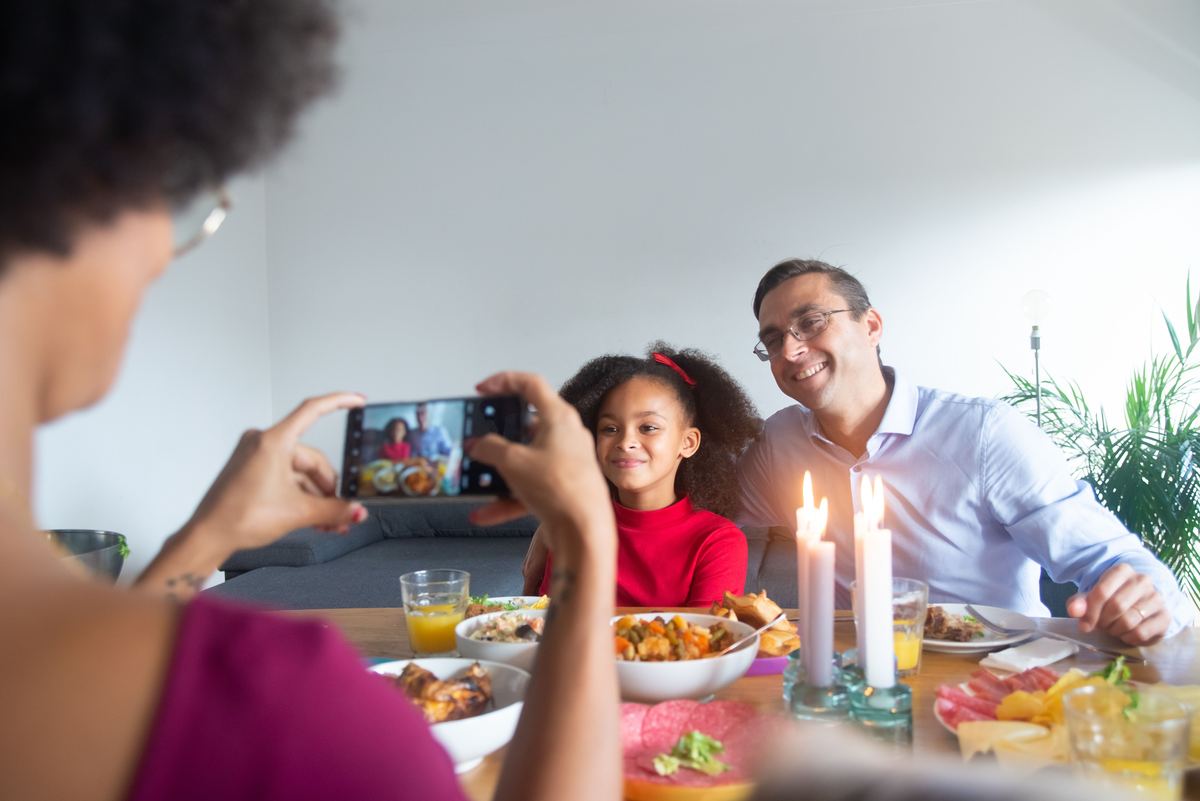 A family at a dinner table with someone holding up a phone