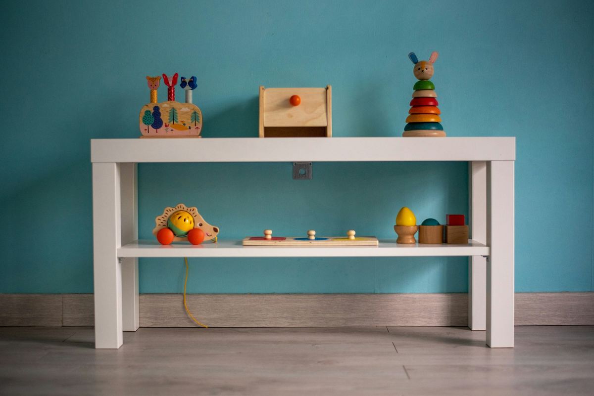 Wooden toys arranged on a low white table against a teal wall