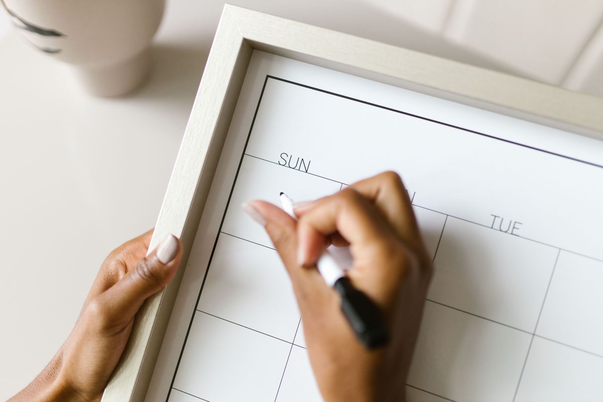 A hand writing on a wall calendar