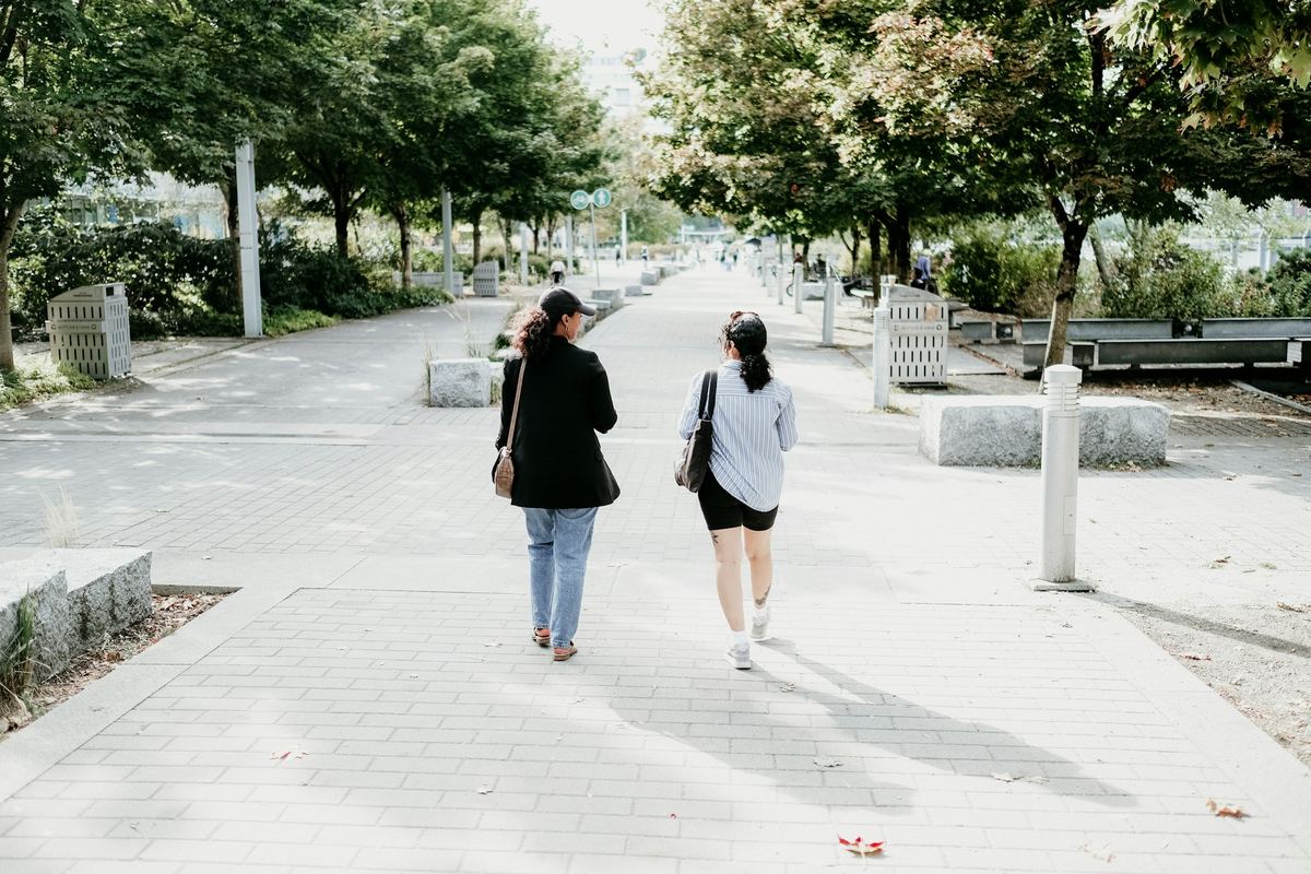 Two people walking together along a tree-lined path