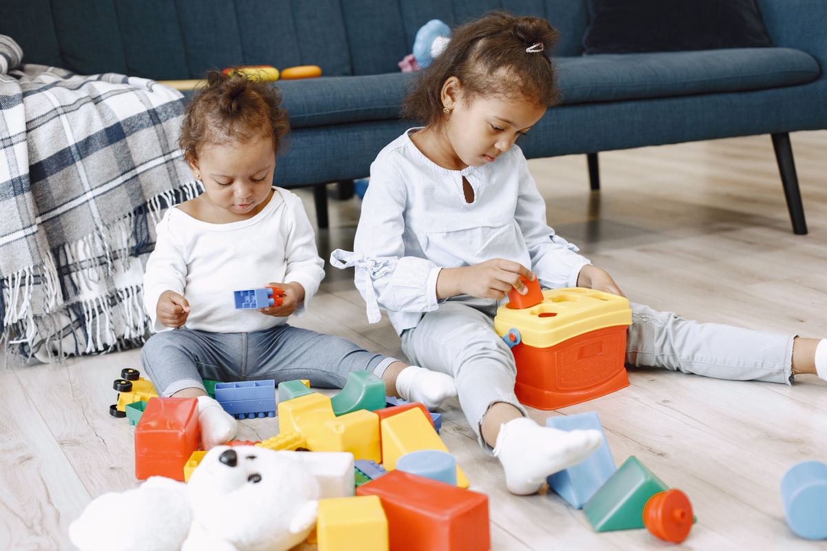 Two young children playing with toys on a rug