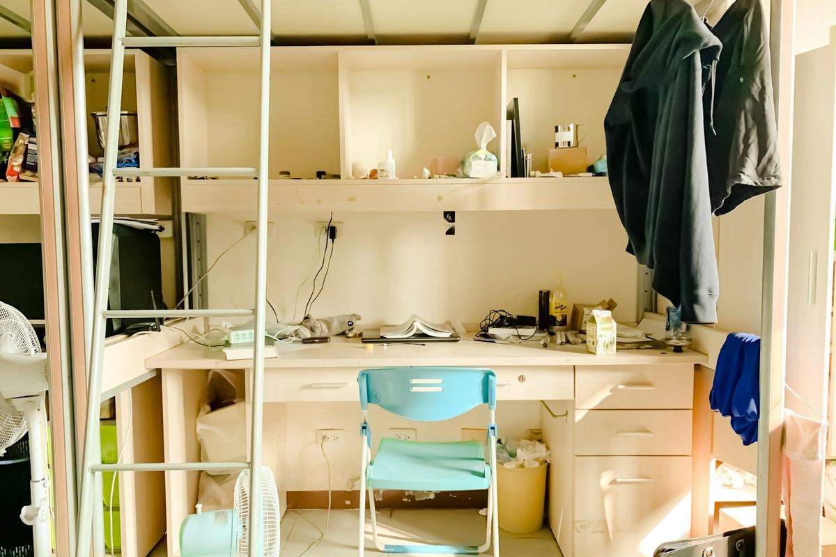 A student room with a desk, chair and shelves in daylight