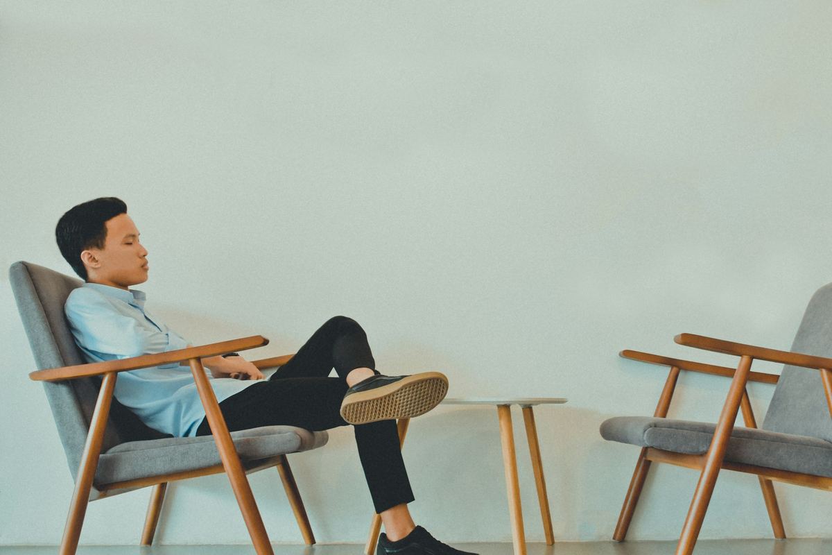 A young person sitting in an armchair in a bright room