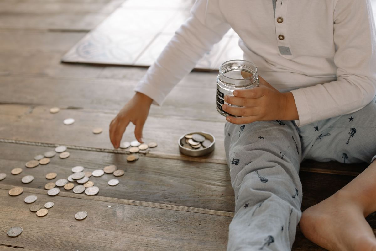 A young child putting coins into a jar