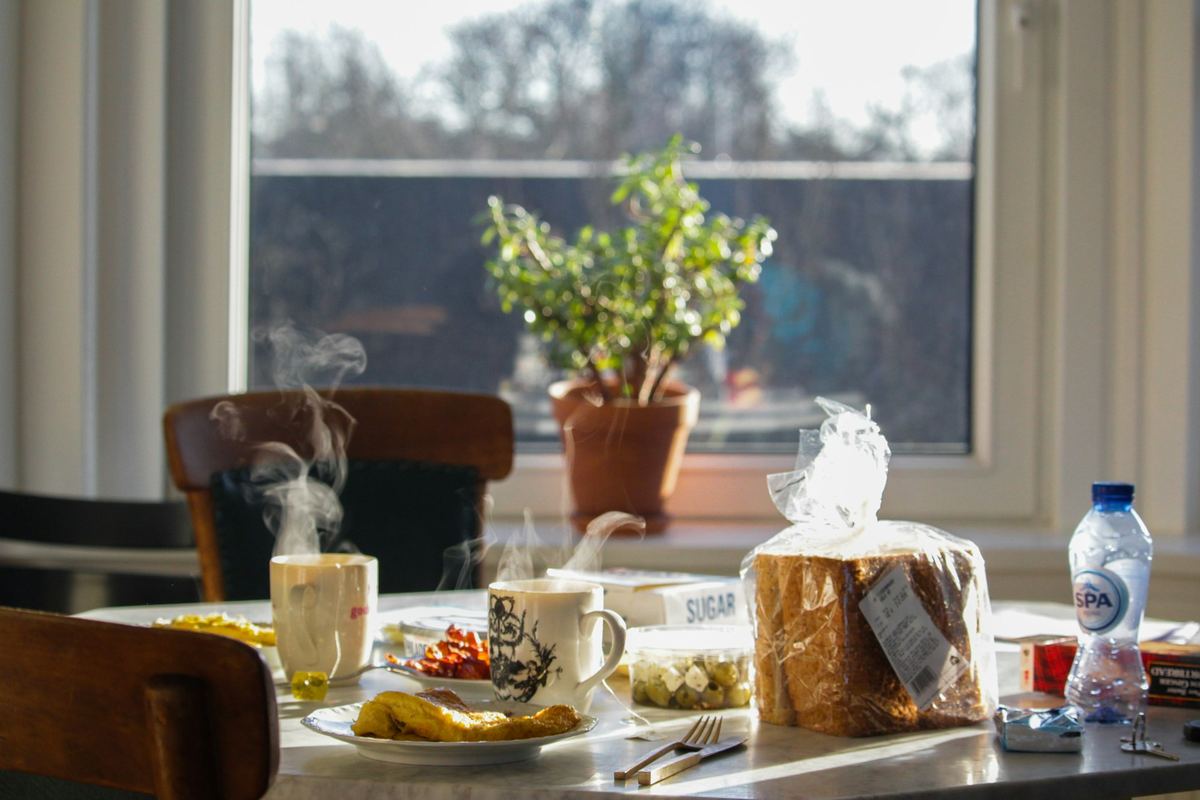 A breakfast table set with food and drinks by a window