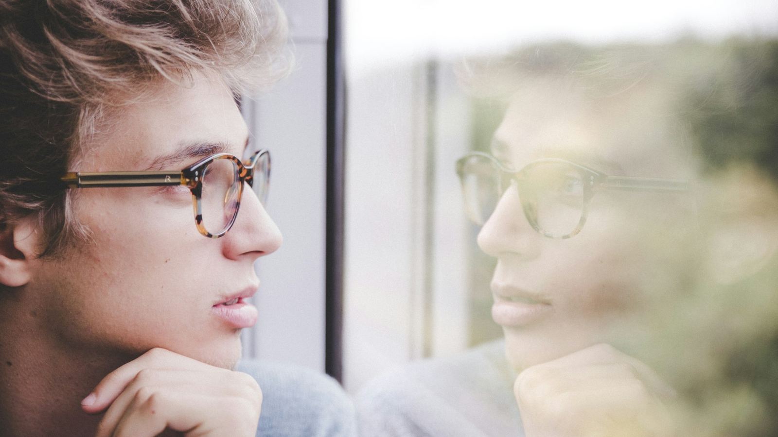 A teenager sitting by a window in daylight