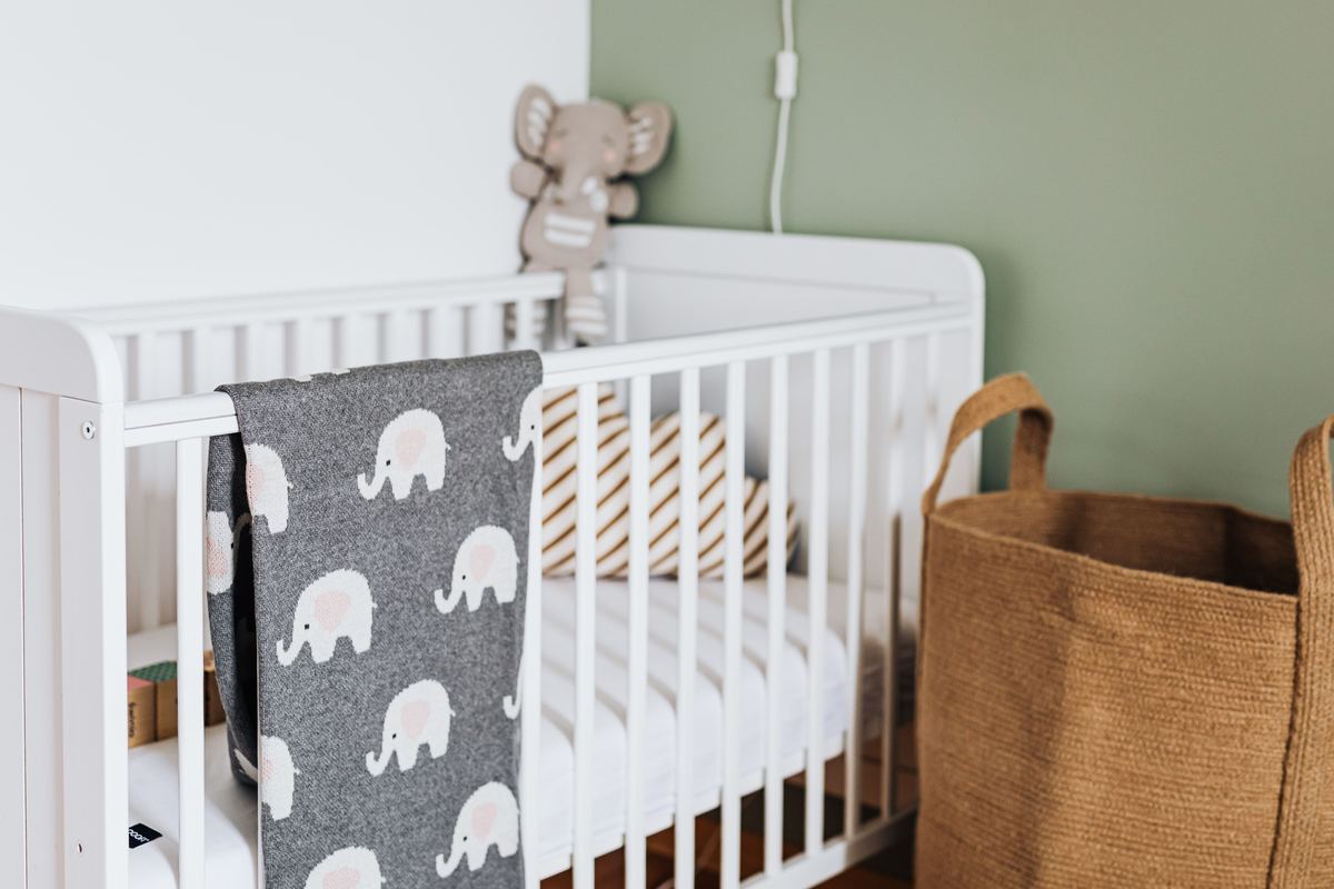 A nursery with a white crib and folded blankets
