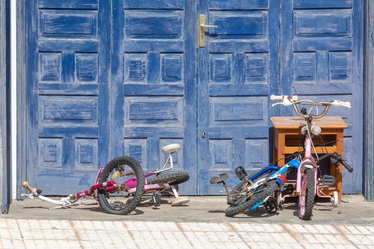 Two children's bicycles parked against a blue garage door