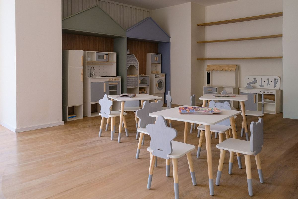 A playroom with small tables, chairs and toy storage