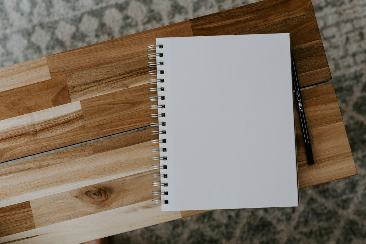 A blank spiral notebook and pen on a wooden table