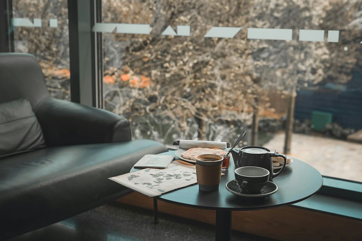 Two mugs on a low table beside an armchair and a window