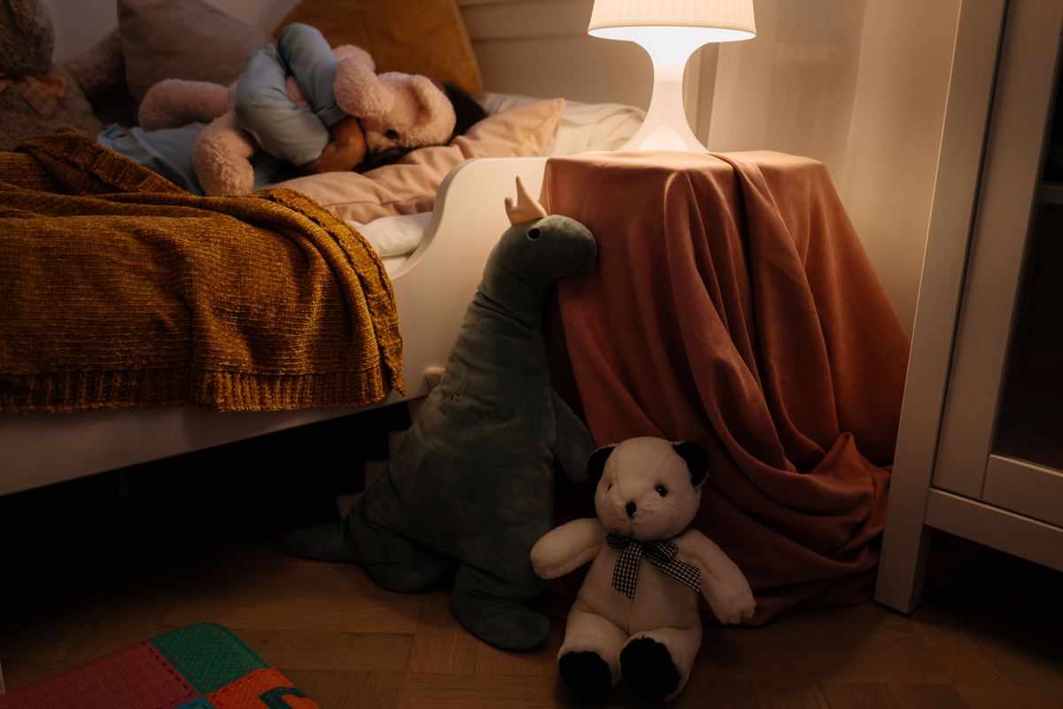 A child's bedroom with soft lamp light and plush toys