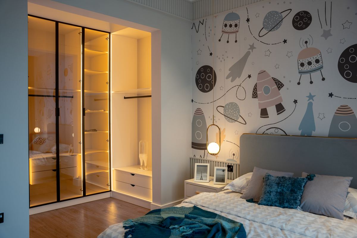 A tidy child's bedroom with patterned wallpaper in daylight