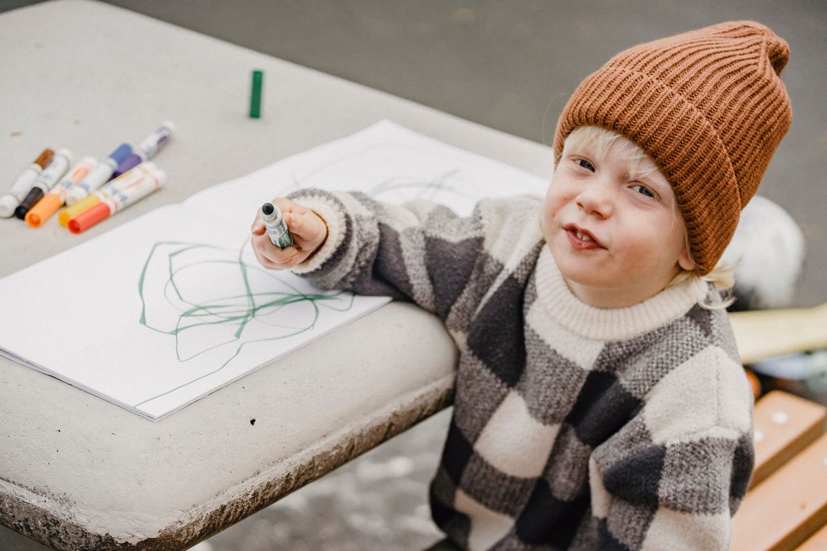 A young child drawing at a table with crayons