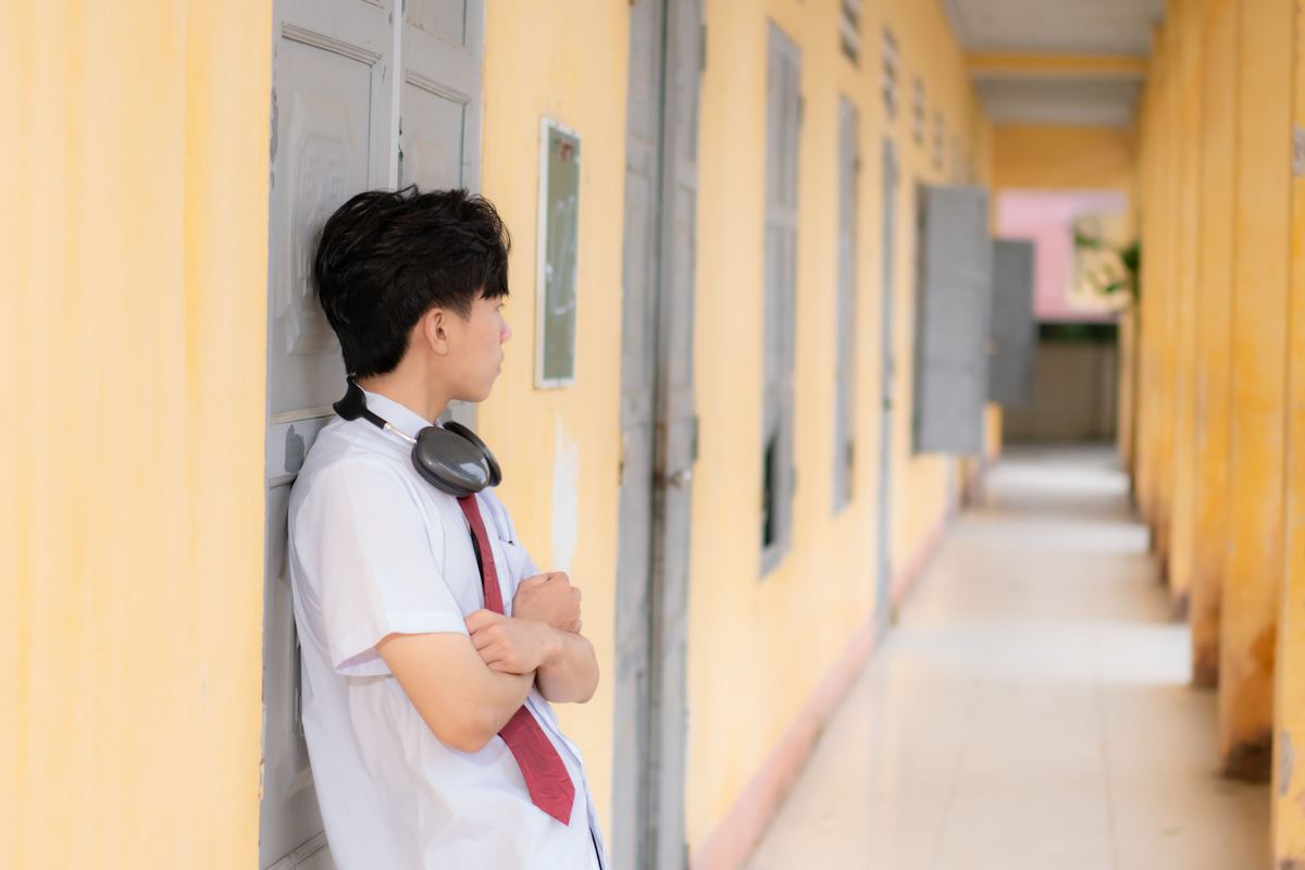 A teenage student leaning against a corridor wall
