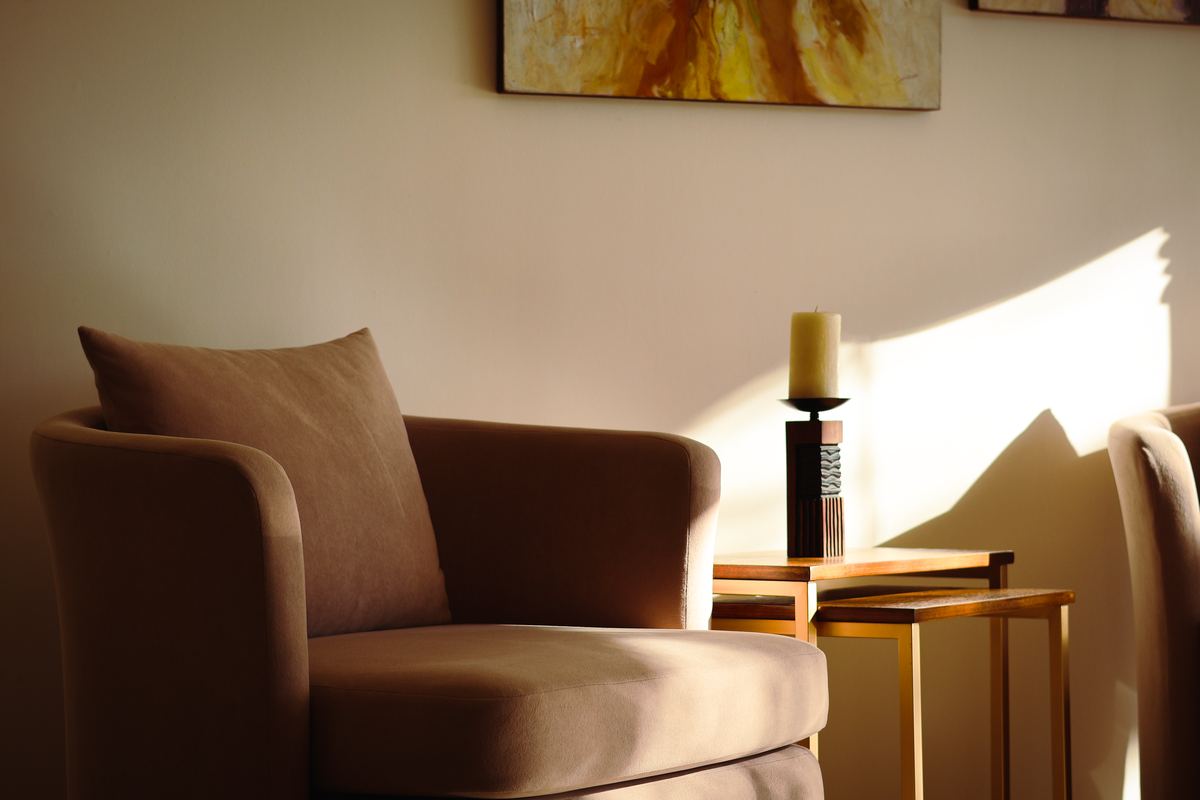 A sunlit corner with an empty armchair and a candle