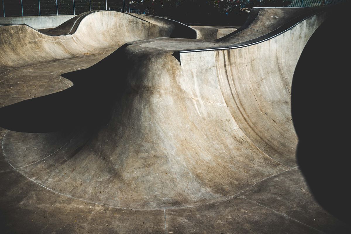 An empty concrete skatepark with curved ramps