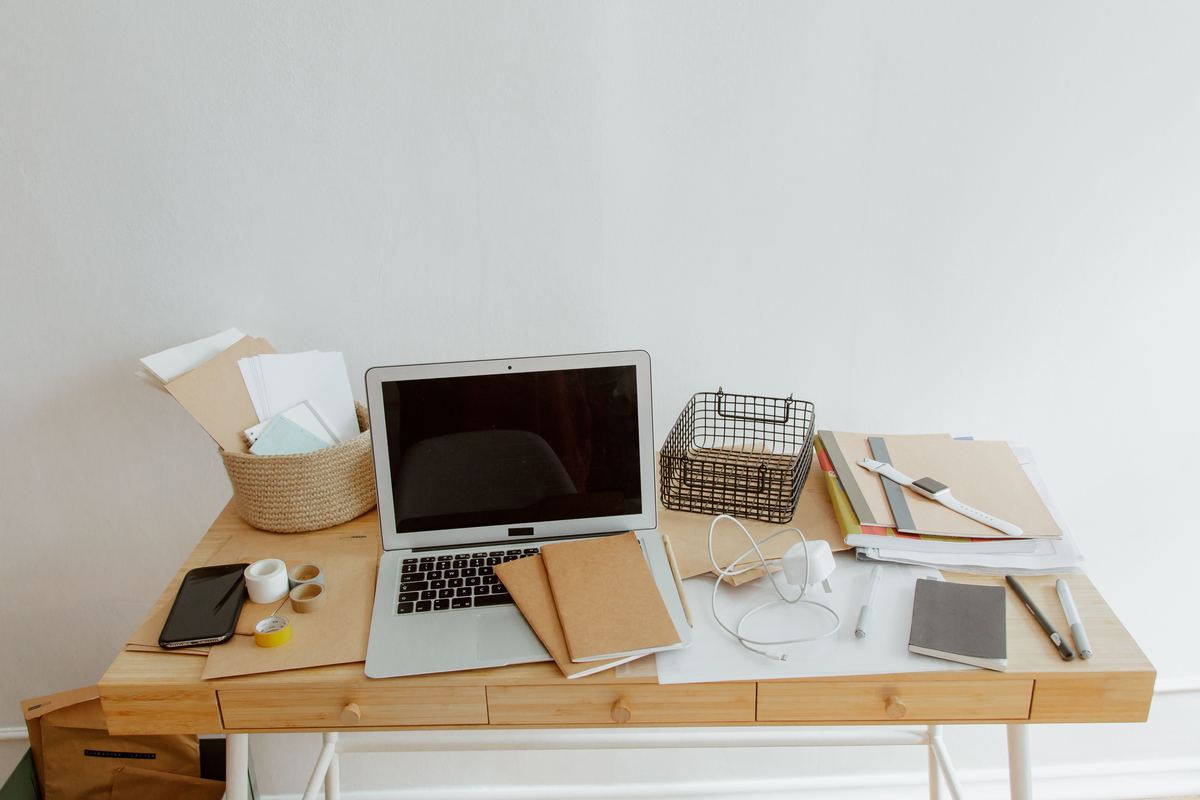 A tidy desk with a laptop, notebooks and supplies