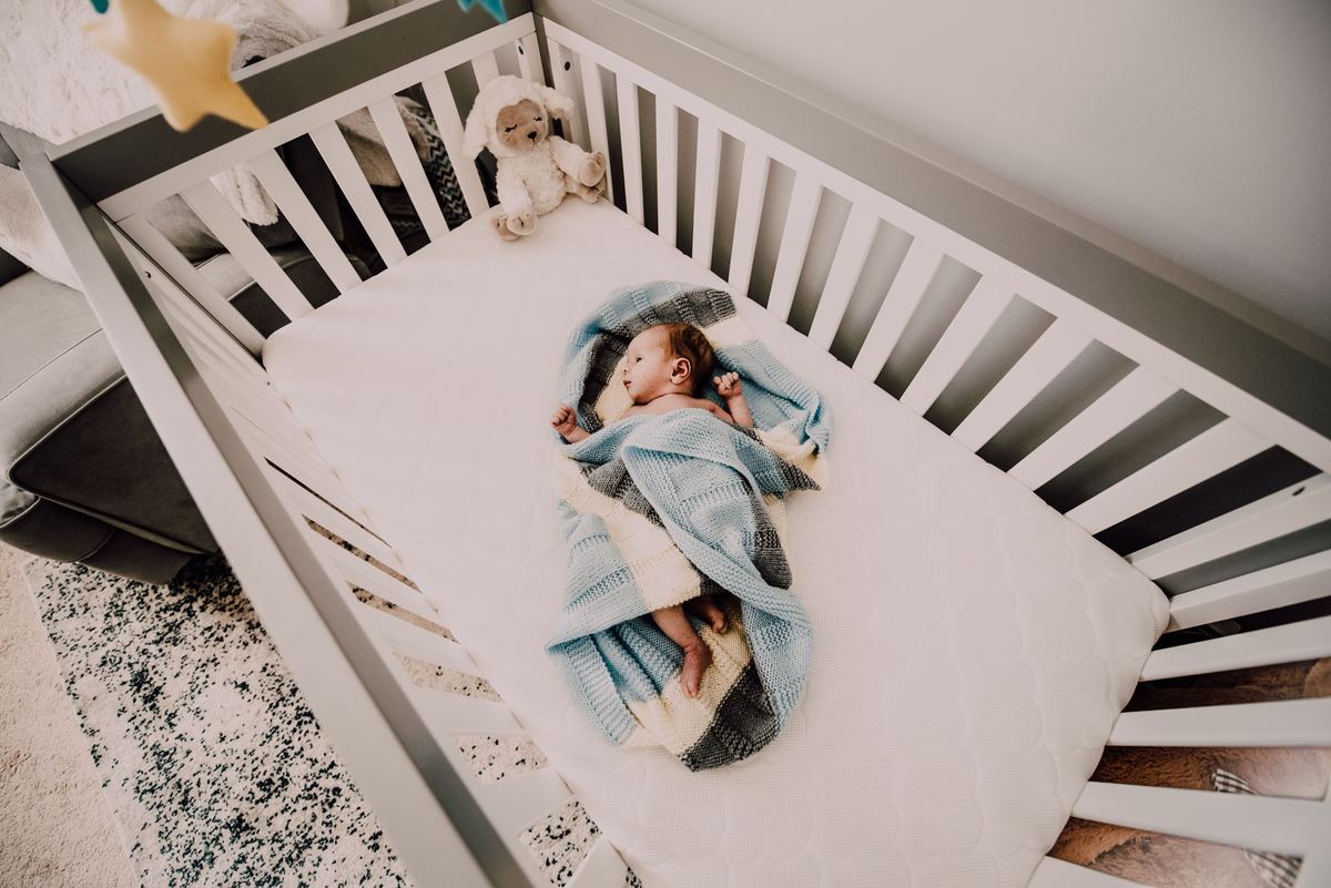 A baby wrapped in a blanket sleeping in a crib