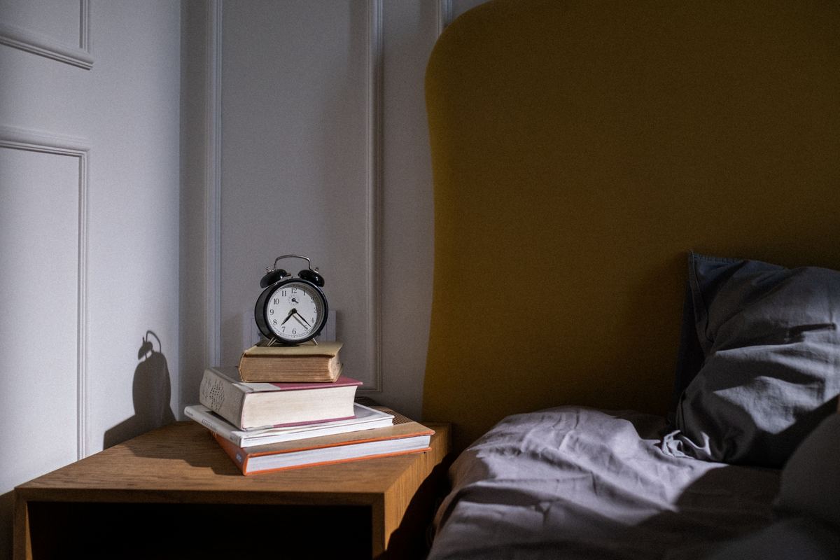 Books and an alarm clock on a bedside table