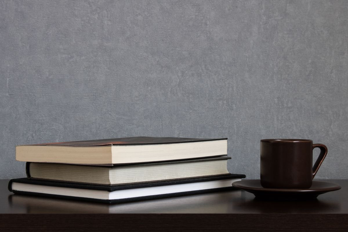A stack of books beside a cup of coffee on a table