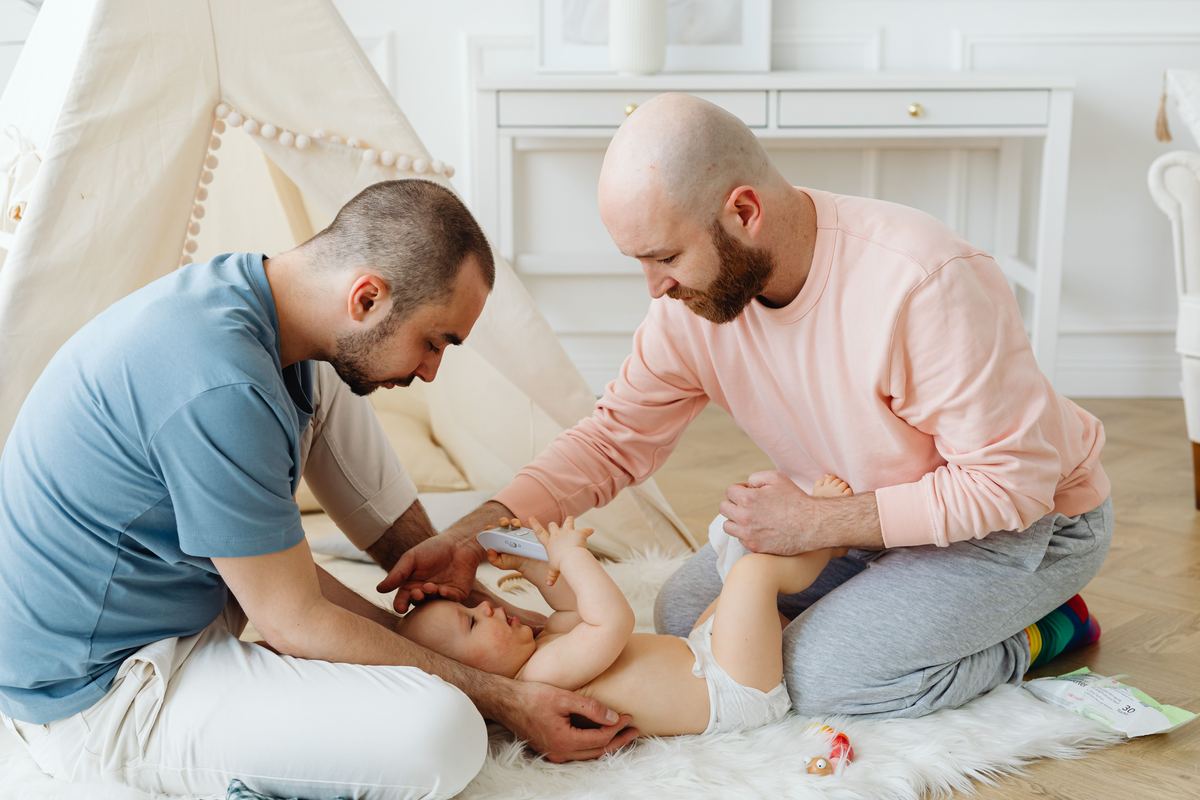 Two parents together caring for their baby at home