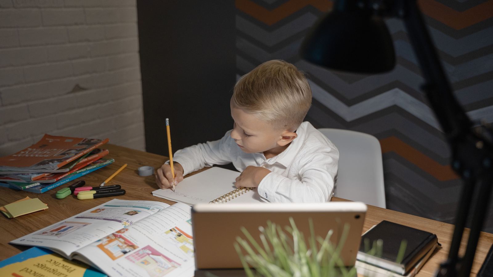 A child writing at a desk with books open in front of them