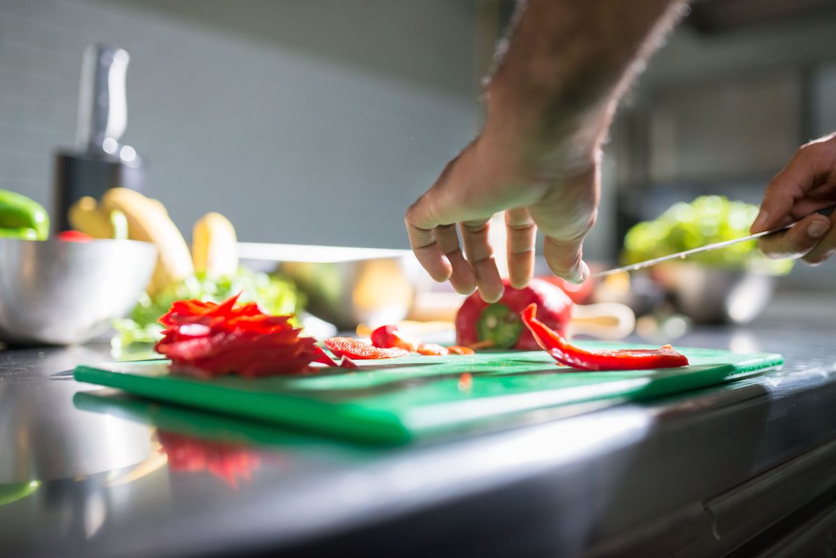 Hands slicing a red pepper on a chopping board